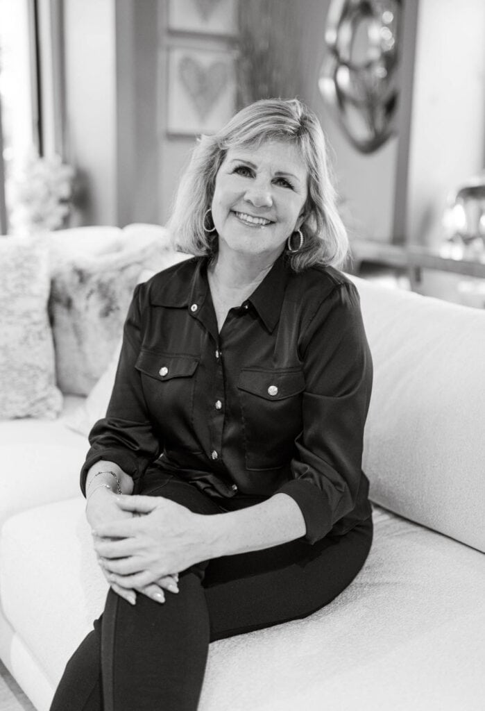 Senior woman sitting on sofa, smiling, in a cozy, styled interior.