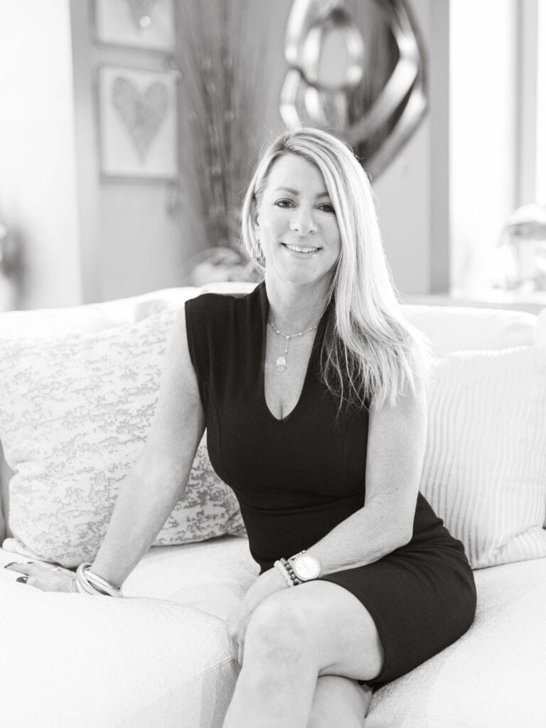Elegant woman sitting on a couch inside a modern home, promoting interior design excellence.