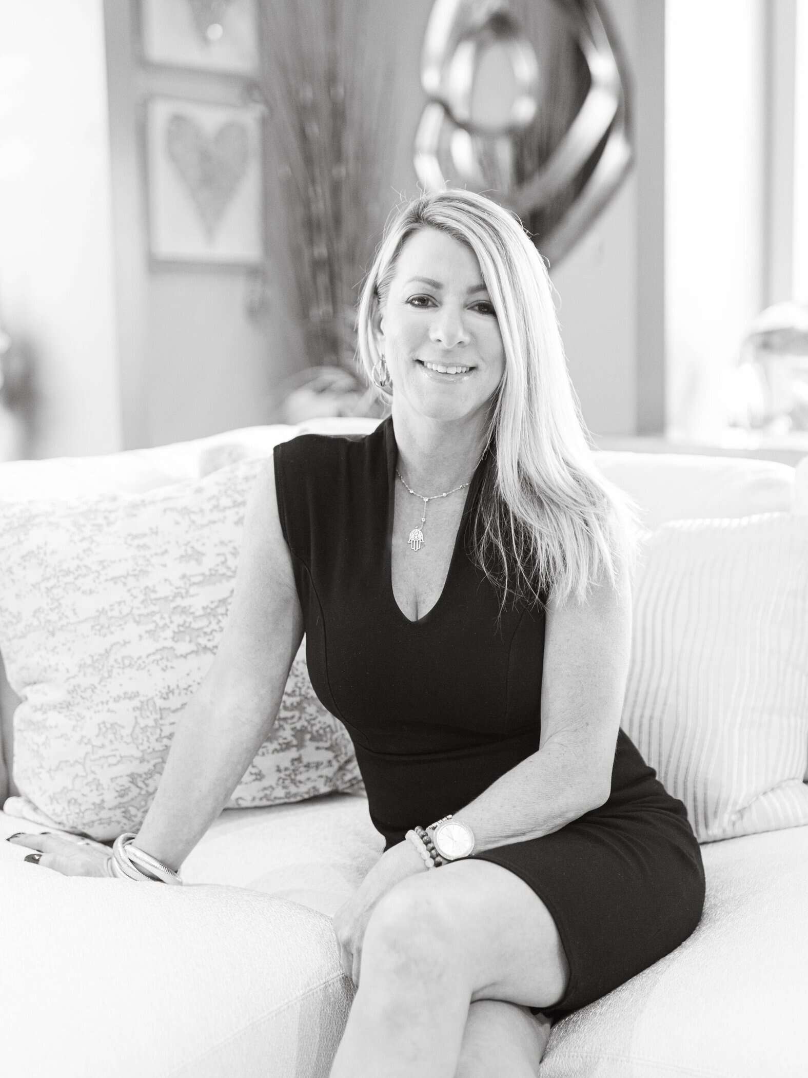 Elegant woman sitting on a couch inside a modern home, promoting interior design excellence.