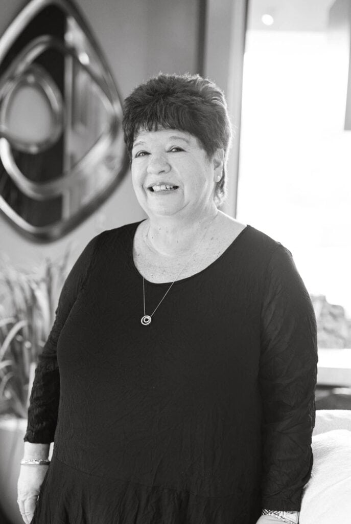Senior woman smiling in professional dress at Brown Design Group office, showcasing interior design expertise.