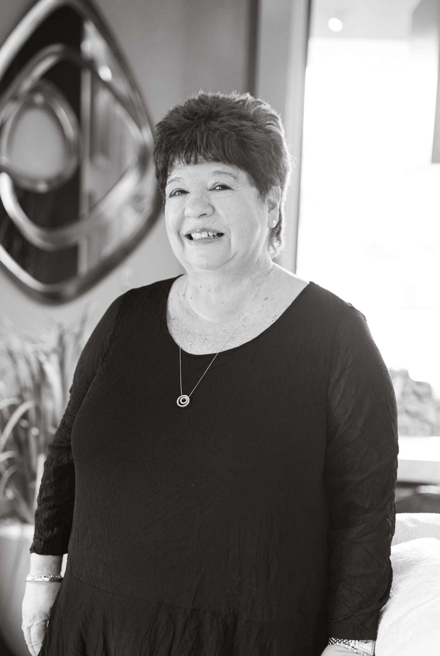 Senior woman smiling in professional dress at Brown Design Group office, showcasing interior design expertise.