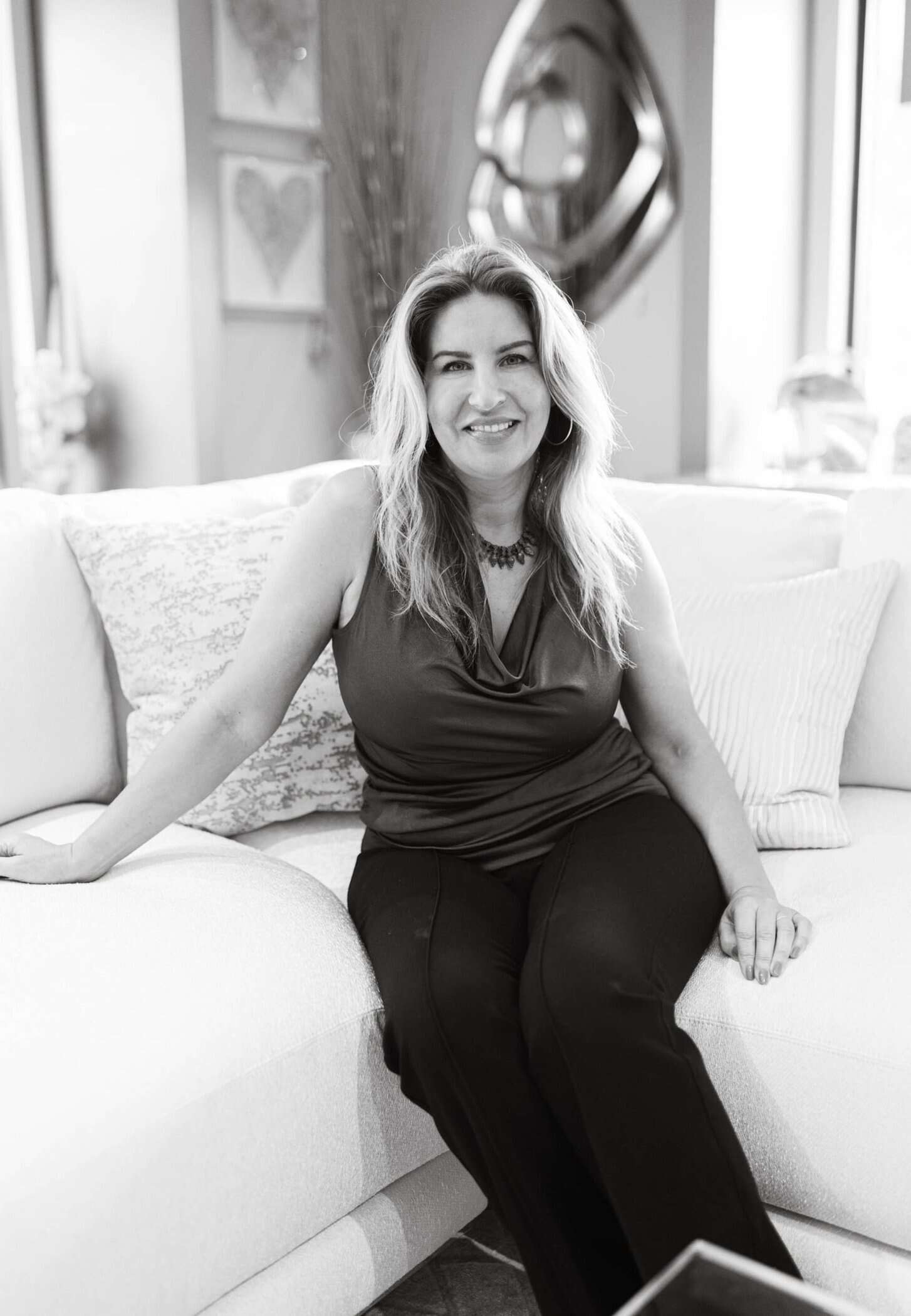 Modern woman sitting on a beige sofa in a well-designed interior.