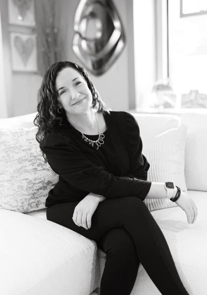 Woman sitting on a couch in a modern home, smiling.