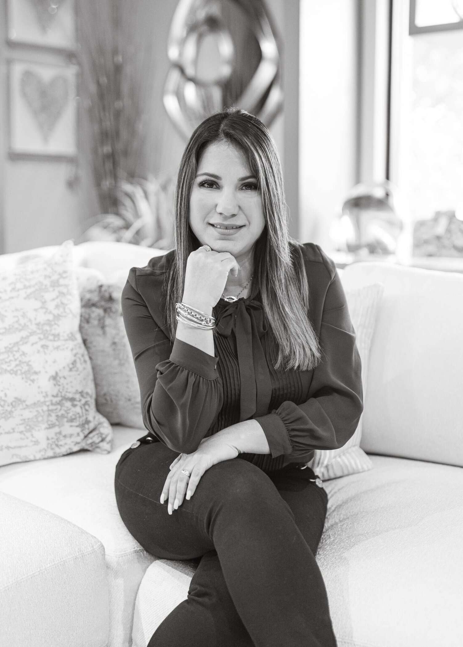 Portrait of a woman sitting on a sofa, professional interior designer, Brown Design Group branding.