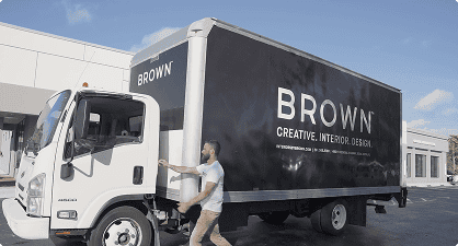 Large mobile billboard truck for Brown Design Group showcasing creative interior design services in a commercial area.